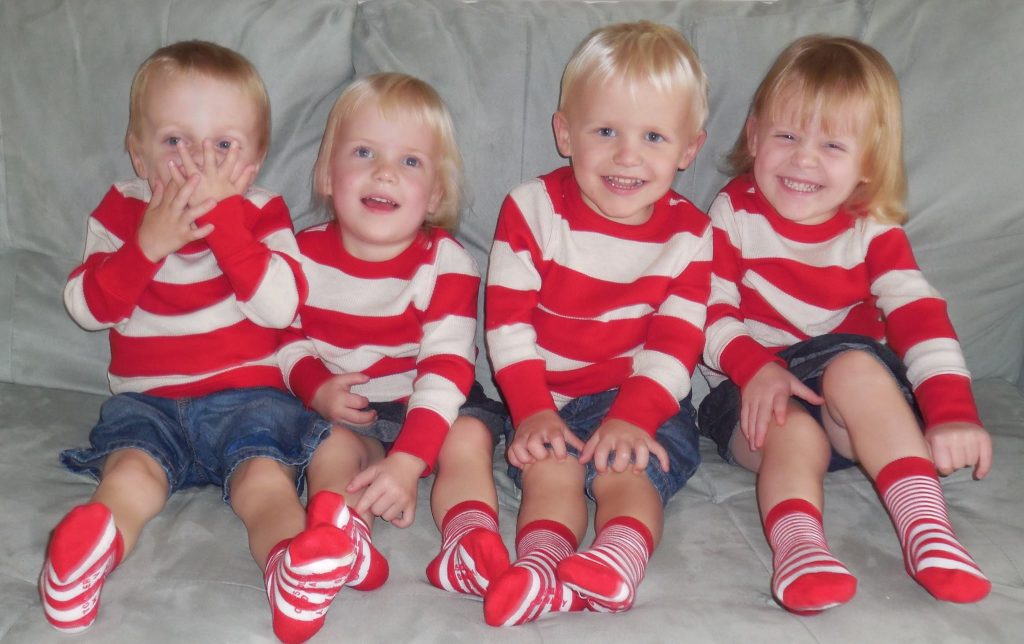 Larson quadruplet toddlers wearing matching red and white striped shirts